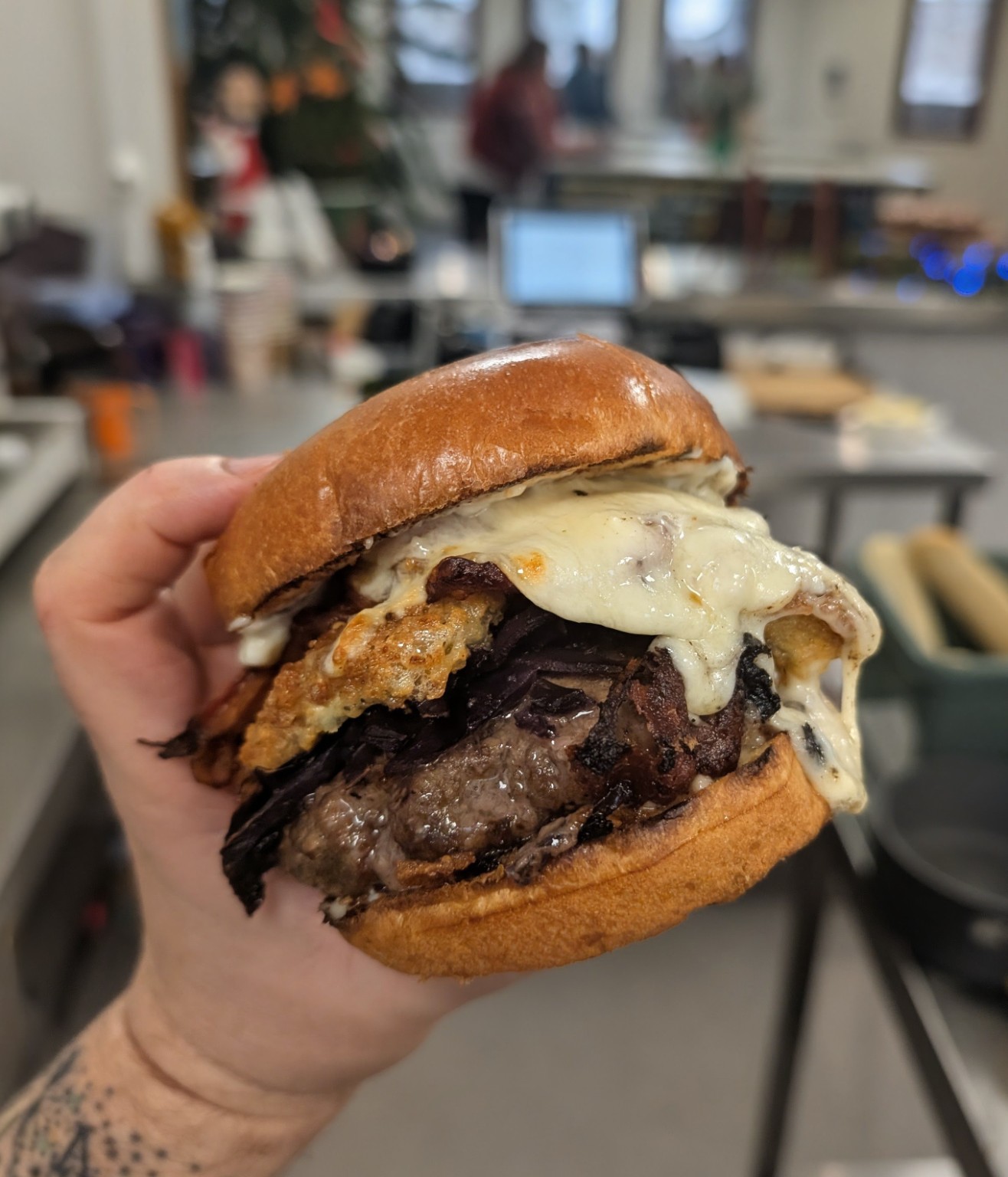 A brioche bun filled with sliced meat and melted cheese at Franco’s café