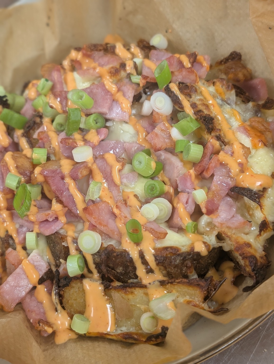 Loaded potatoes topped with bacon, melted cheese, spring onions and sauce