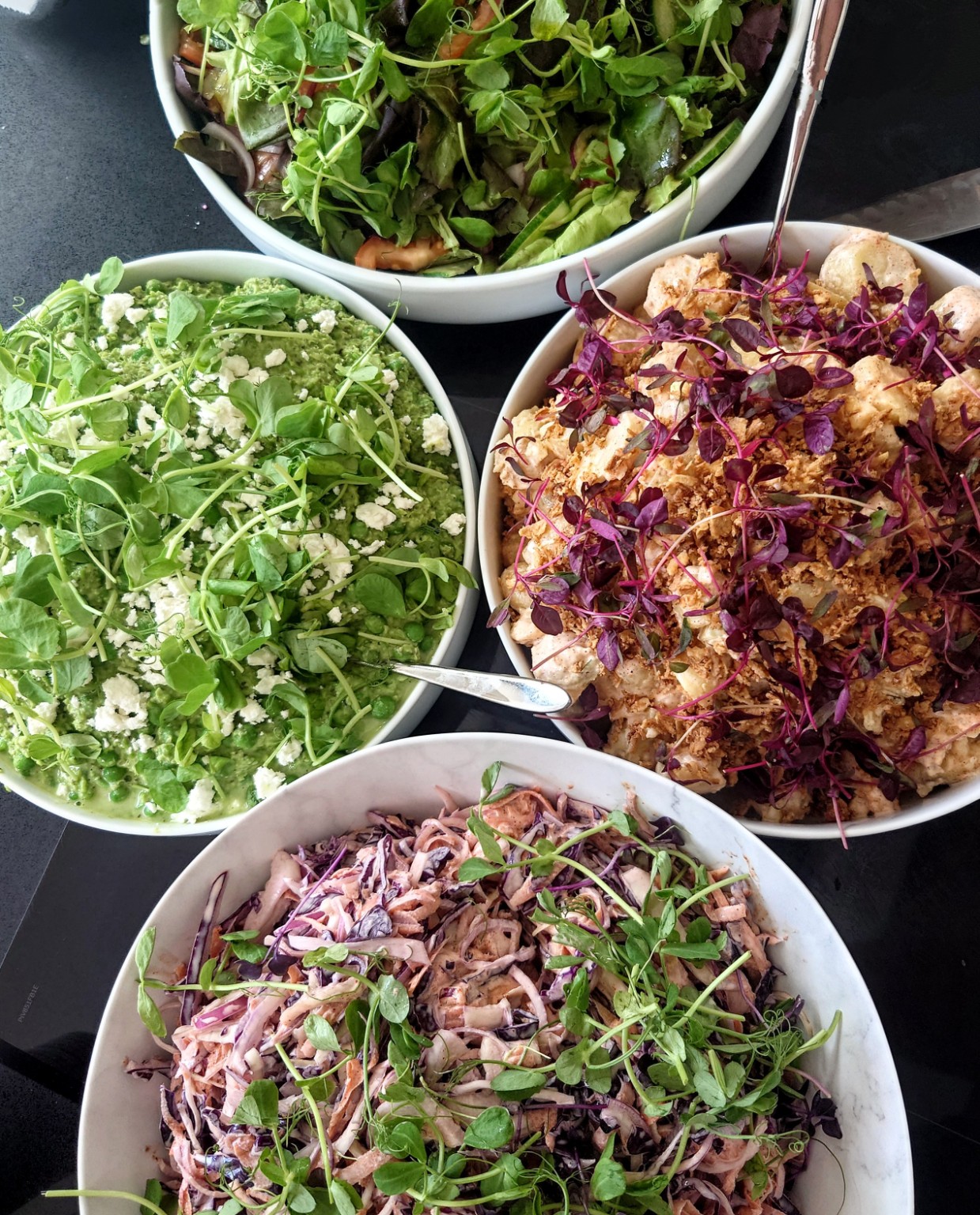 Bowls of colourful salads and slaw finished with fresh shoots