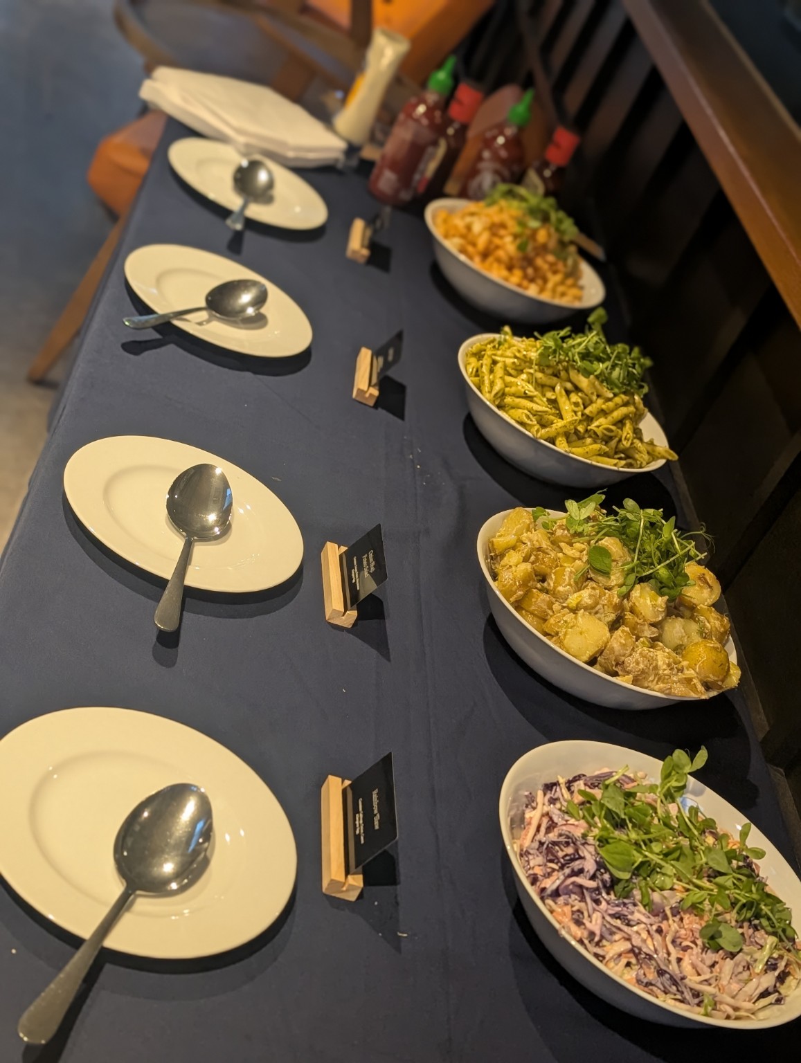 A buffet table set with bowls of pasta salad, potato salad and slaw