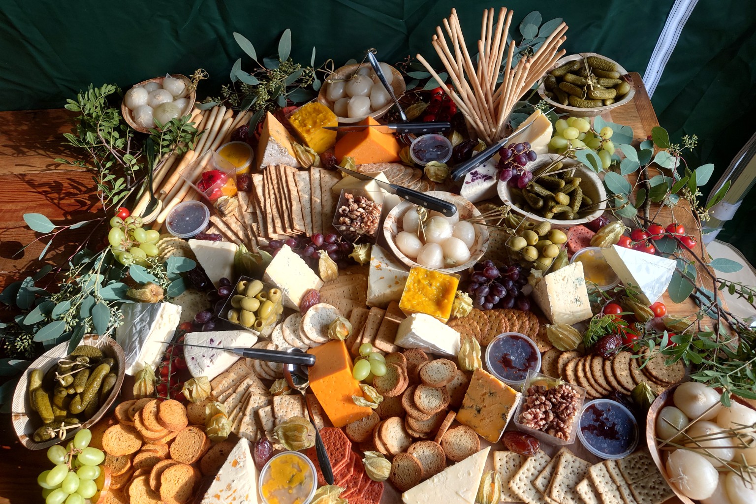 A grazing table filled with cheeses, crackers, grapes, olives and pickles
